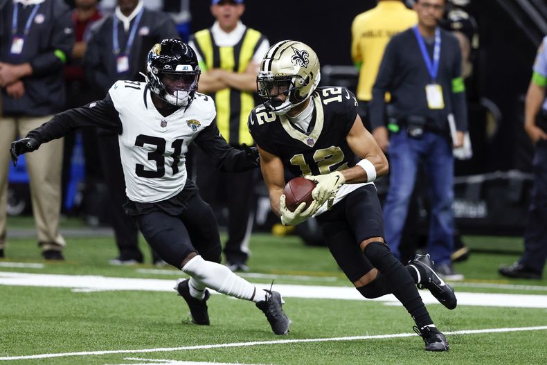 El receptor de los Saints de Nueva Orleans Chris Olave hace un cambio para superar al cornerback de los Jaguars de Jacksonville Darious Williams tras una recepción durante el encuentro del jueves 19 de octubre del 2023. (AP Foto/Butch Dill)