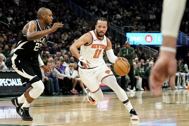 Jalen Brunson (11), de los Knicks de Nueva York, lleva el balón a la canasta, ante Khris Middleton, izquierda, de los Bucks de Milwaukee, durante la primera mitad del juego de baloncesto de la NBA, el domingo 7 de abril de 2024, en Milwaukee. (AP Foto/Aaron Gash)