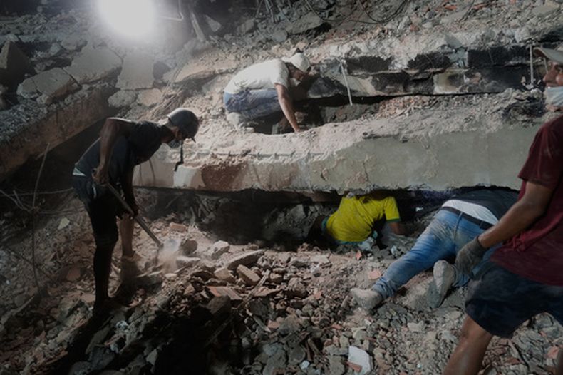 La familia Núñez busca a un familiar entre los escombros de un edificio colapsado por los sismos, el jueves 9 de julio de 2026, en La Guaira, Venezuela. (AP Foto/Ariana Cubillos)