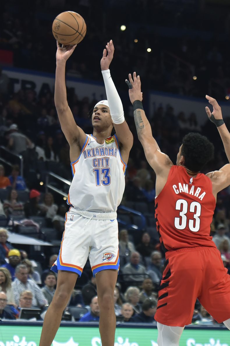 El alero del Thunder de Oklahoma City, Ousmane Dieng (13), dispara junto al alero de los Trail Blazers de Portland, Toumani Camara (33), durante la segunda mitad del partido de baloncesto de la NBA, el jueves 11 de enero de 2024, en Oklahoma City. (AP Foto/Kyle Phillips)