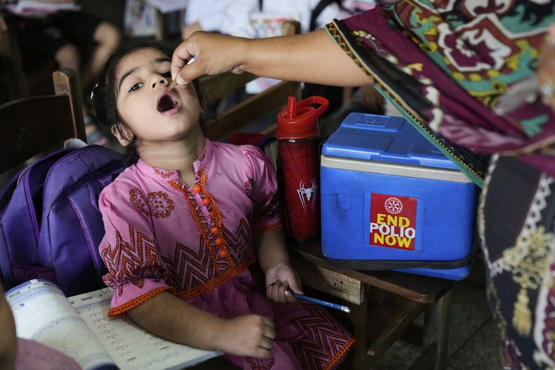 Una trabajadora de salud administra una vacuna para la polio a una niña en una escuela en Lahore, Pakistán el lunes 21 de abril de 2025. (AP Foto/K.M. Chaudary)