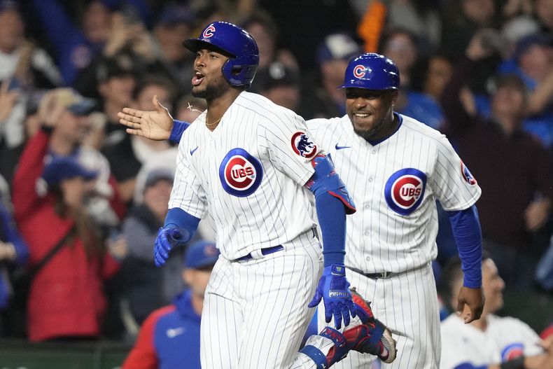 El entrenador de 3ra base de los Cachorros de Chicago, derecha, sonríe luego que Alexander Canario conectara un grand slam ante los Piratas de Pittsburgh en la 8va entrada. Martes 19 de septiembre de 2023. (AP Foto/Charles Rex Arbogast)
