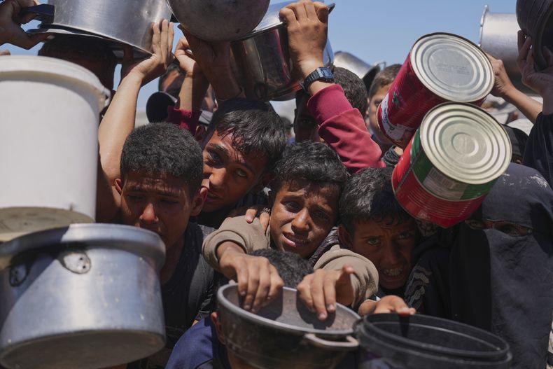 Palestinos tratan de obtener alimentos donados en una cocina comunitaria en Jan Yunis, en el sur de la Franja de Gaza, el lunes 2 de junio de 2025. (AP Foto/Abdel Kareem Hana)