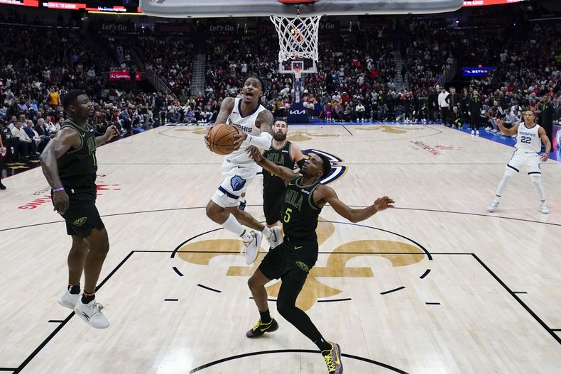 Ja Morant, de los Grizzlies de Memphis, ataca el aro en contra de los Pelicans de Nueva Orleans, superando la marca defensiva de Herbert Jones (5) en la segunda mitad del juego de baloncesto de la NBA, el martes 19 de diciembre de 2023, en Nueva Orleans. Los Grizzlies ganaron 115-113. (AP Foto/Gerald Herbert)