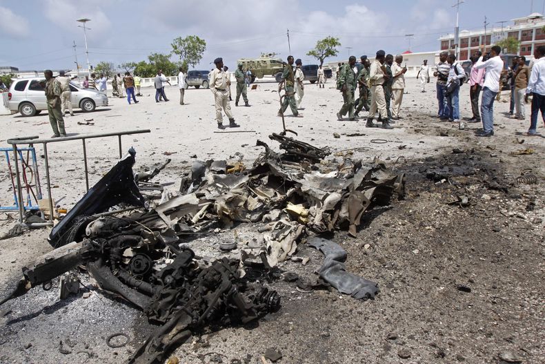 Soldados somal&iacute;es rodean los restos de un coche bomba suicida cerca del parlamento en Mogadiscio, Somalia, s&aacute;bado 5 de julio de 2014. El atentado, que dej&oacute; cuatro muertos, fue reivindicado por el grupo extremista al-Shahab. (AP Foto/F