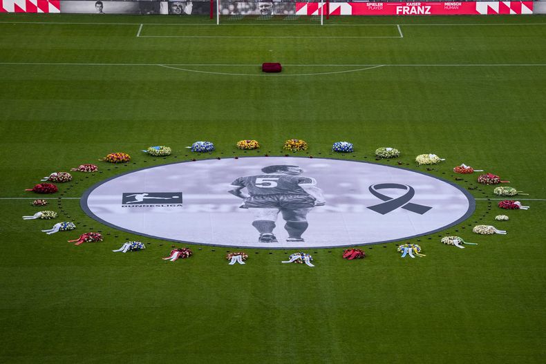 Arreglos florales rodean una fotografía del grande del Bayern Munich y Alemania Franz Beckenbauer en el centro del campo del Allianz Arena durante el memorial del viernes 19 de enero del 2024. (AP Foto/Matthias Schrader)