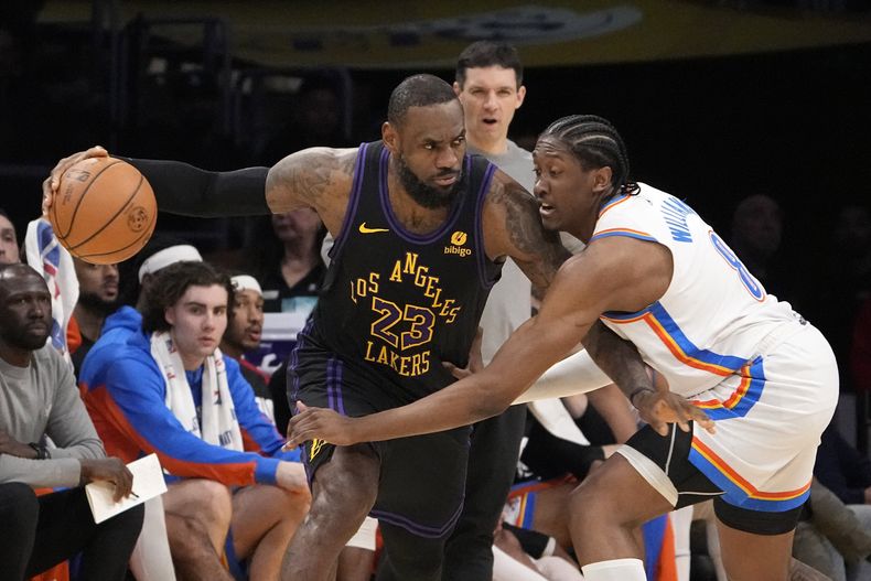 Jalen Williams, del Thunder de Oklahoma City (derecha), trata de sacarle la bola a LeBron James, de los Lakers de Los Ángeles, durante la primera mitad del juego de la NBA que enfrentó a ambos equipos, el 15 de enero de 2024, en Los Ángeles. (AP Foto/Mark J. Terrill)