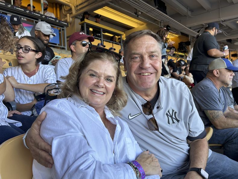 Dwight y Renee Schmidt, padres del lanzador de los Yankees de Nueva York, Clarke Schmidt, sentados en las gradas previo al Juego 2 de la Serie Mundial ante los Dodgers de Los Ángeles, el sábado 26 de octubre de 2024, en Los Ángeles. (AP Foto/Doug Padilla)