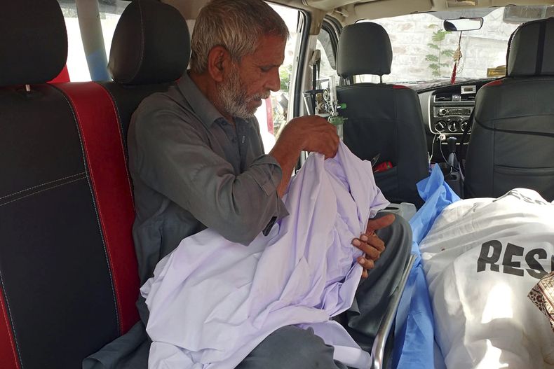 Un familiar lleva el cuerpo de un niño, que murió cuando un autobús de pasajeros cayó por un barranco, dentro de una ambulancia en un hospital de Kahuta, Pakistán, el domingo 25 de agosto de 2024. (AP Foto/Mohammad Yousaf)