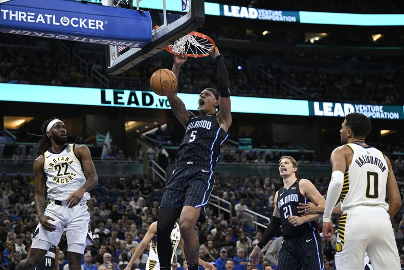 Paolo Banchero (5), del Magic de Orlando, clava el balón entre Isaiah Jackson (22) y Tyrese Haliburton (0), de los Pacers de Indiana, durante la primera mitad del juego de baloncesto de la NBA, el lunes 28 de octubre de 2024, en Orlando, Florida. (AP Foto/Phelan M. Ebenhack)