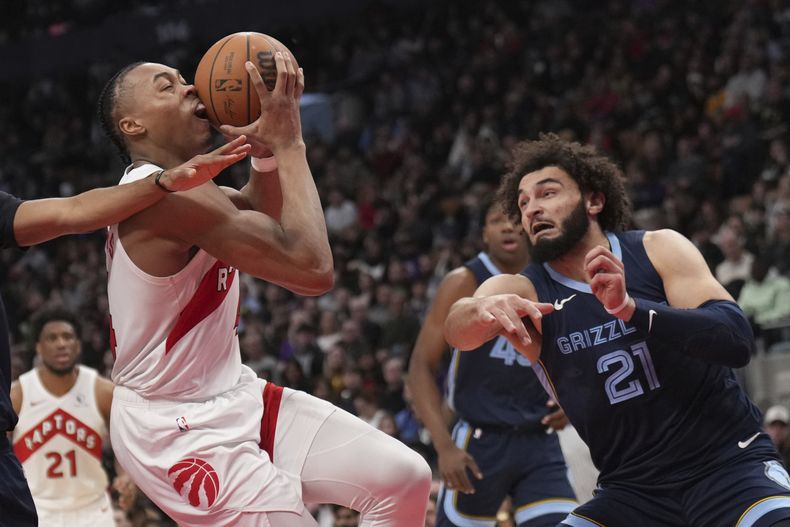 Scottie Barnes, izquierda, de los Raptors de Toronto, intenta pasar sobre David Roddy (21), de los Grizzlies de Memphis, durante la segunda mitad del juego de baloncesto de la NBA en Toronto, el lunes 22 de enero de 2024. (Nathan Denette/The Canadian Press vía AP)