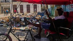 Un conductor de bicitaxi espera a los clientes junto a un montón de basura en La Habana, Cuba, el lunes 1 de junio de 2026. (Foto AP/Ramón Espinosa)