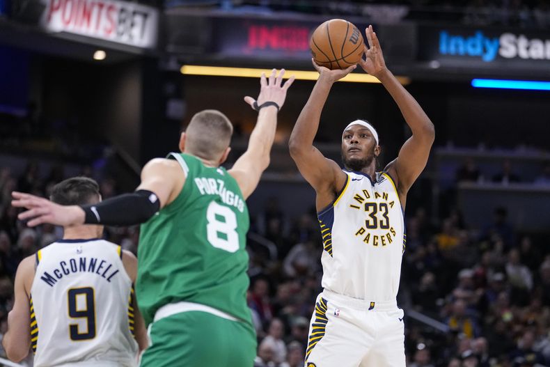 El pívot de los Pacers de Indiana Myles Turner lanza el balón sobre el pívot de los Celtics de Boston Kristaps Porzingis en el encuentro del lunes 8 de enero del 2024. (AP Foto/Michael Conroy)