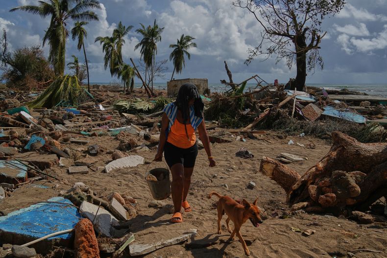 Una mujer y su perro caminan entre las ruinas de las casas destruidas por el huracán Melissa en Boca de dos Ríos, Cuba, el jueves 30 de octubre de 2025. (Foto AP/Ramón Espinosa)