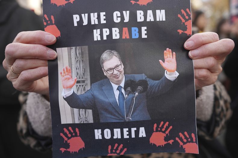 Una mujer con el retrato del presidente serbio Aleksandar Vucic con la leyenda “Tienes sangre en las manos”, al conmemorar las víctimas del derrumbe de un techo, en Belgrado, el 6 de diciembre del 2024. (AP foto/Darko Vojinovic)