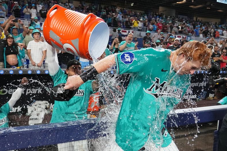 Owen Caissie, de los Marlins de Miami (a la derecha), es bañado en agua tras anotar un jonrón de dos carreras que le dio la victoria a su equipo sobre los Rockies de Colorado en un partido de béisbol el domingo 29 de marzo de 2026 en Miami. (Foto AP/Lynne Sladky)