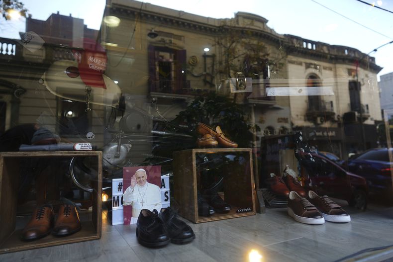 Una fotografía del fallecido Papa Francisco aparece en la vidriera de la zapatería Muglia junto al modelo de zapatos que usaba Jorge Bergoglio en el barrio de Flores, donde creció, en Buenos Aires, Argentina, el jueves 24 de abril de 2025. (AP Foto/Natacha Pisarenko)