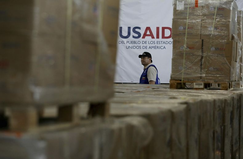 ARCHIVO - Un hombre pasa frente a cajas de ayuda humanitaria de USAID en un almacén en las afueras de Cúcuta, Colombia, el 21 de febrero de 2019, en la frontera con Venezuela. (AP Foto/Fernando Vergara)