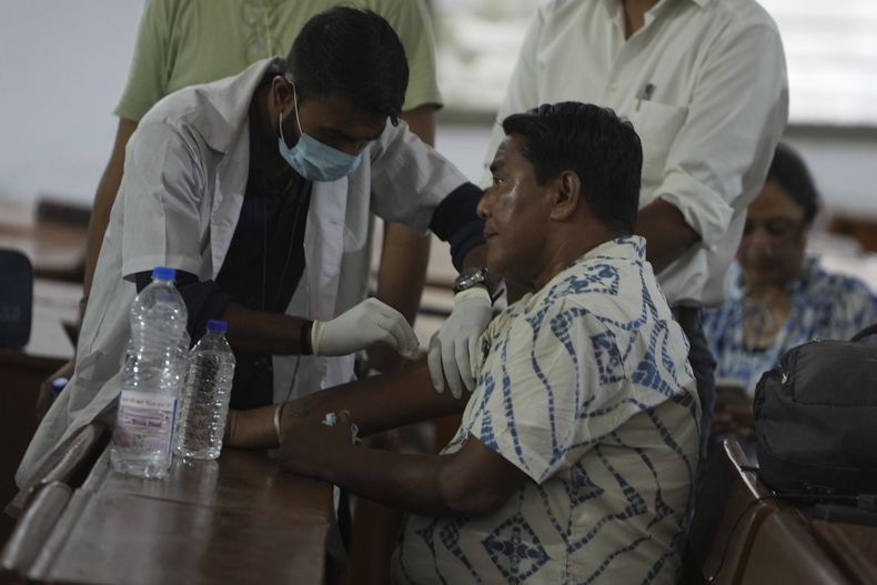 Un trabajador médico toma una muestra de ADN a un familiar de una víctima del avión estrellado en la ciudad noroccidental india de Ahmedabad en el estado de Gujarat, el viernes 13 de junio de 2025. (AP Foto/Ajit Solanki)