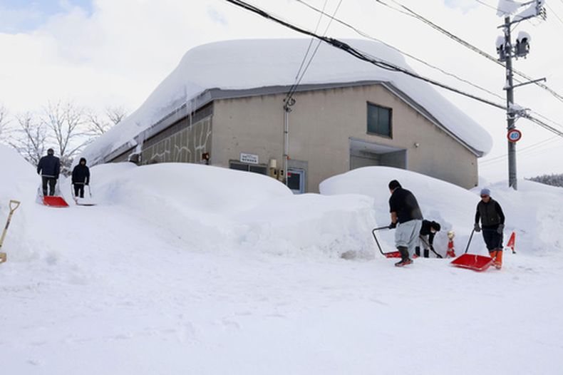 Gente despeja nieve cerca de un edificio en Aomori, en el norte de Japón, el lunes 2 de febrero de 2026. (Kyodo News via AP)
