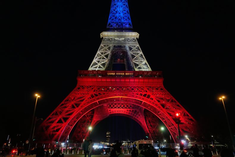La torre Eiffel se ve iluminada con los colores de la bandera nacional francesa en París, el miércoles 12 de noviembre de 2025, para homenajear a las víctimas de los ataques terroristas en la sala de conciertos Bataclan, cafeterías y los alrededores del estadio nacional 10 años antes. (AP foto/Michel Euler)