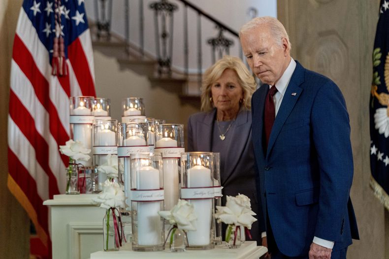 El presidente Joe Biden, acompañado por la primera dama Jill Biden, observa flores y velas con los nombres de las víctimas de la masacre en una escuela primaria de Uvalde, Texas, en el primer aniversario del incidente, el miércoles 24 de mayo de 2023, en la Casa Blanca, Washington. (AP Foto/Andrew Harnik)