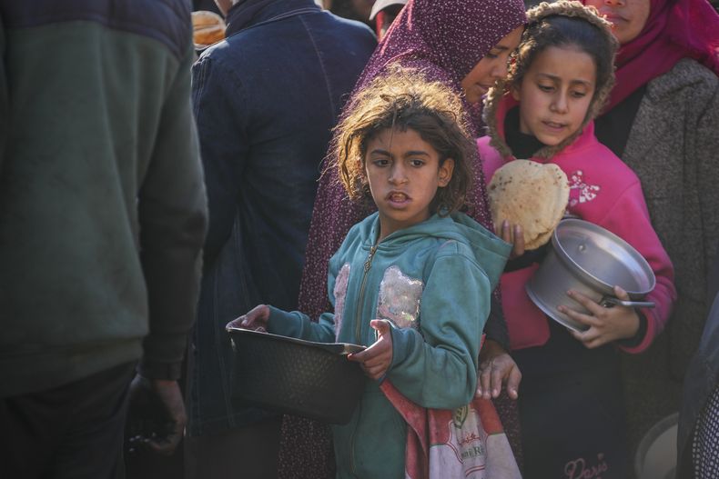 Niñas palestinas recogen comida donada en un centro de distribución de alimentos de Deir al-Balah, el jueves 2 de enero de 2025, en el centro de la Franja de Gaza. (AP Foto/Abdel Kareem Hana)