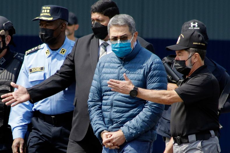 ARCHIVO - El expresidente hondureño Juan Orlando Hernández, segundo de la derecha, es conducido esposado a un avión que lo espera para su extradición a EEUU, en una base aérea de Tegucigalpa, Honduras, el 21 de abril de 2022. (AP Foto/Elmer Martínez/Archivo)
