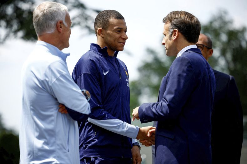 El presidente francés Emmanuel Macron (derecha) saluda al delantero Kylian Mbappé junto al técnico nacional Didier Deschamps en la ciudad deportiva de la selección, el lunes 3 de junio de 2024, en Clairefontaine. (Sarah Meyssonnier/Pool Foto vía AP)