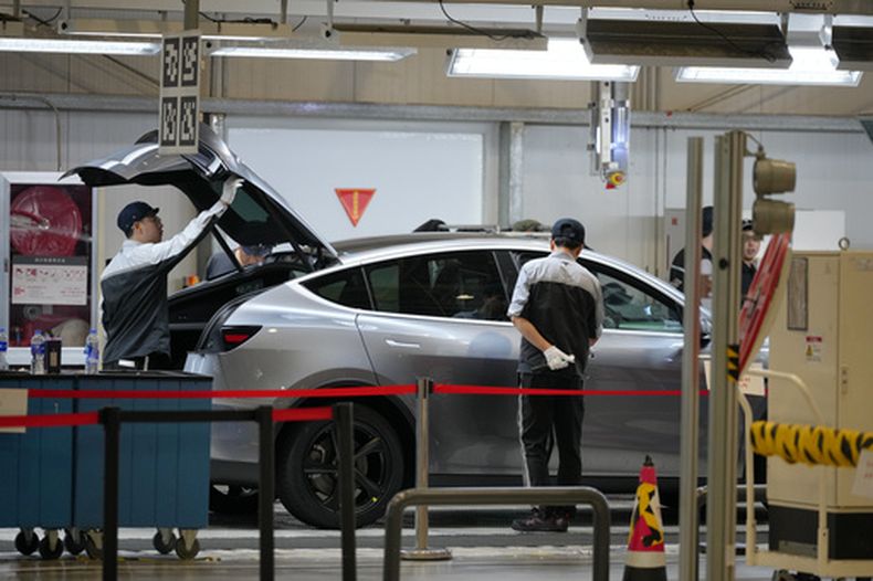 Trabajadores revisan el Modelo Y de Tesla en una línea de producción en la Tesla Gigafactory durante una visita a los medios en Shanghái, China, el martes 14 de abril de 2026. (AP Foto/Andy Wong)