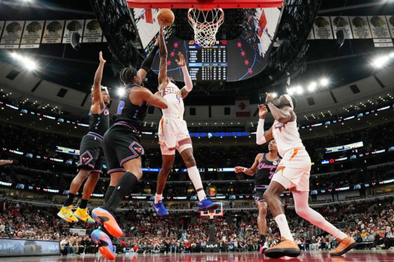 Jalen Green (4), guardia de el Suns de Phoenix, se dirige hacia la canasta ante la defensa de Guerschon Yabusele (28), delantero de los Bulls de Chicago, yCollin Sexton (izquierda), guardia de los Bulls de Chicago, durante la primera mitad de un juego de baloncesto de la NBA, en Chicago, el domingo 5 de abril de 2026. (Foto AP/Nam Y. Huh)