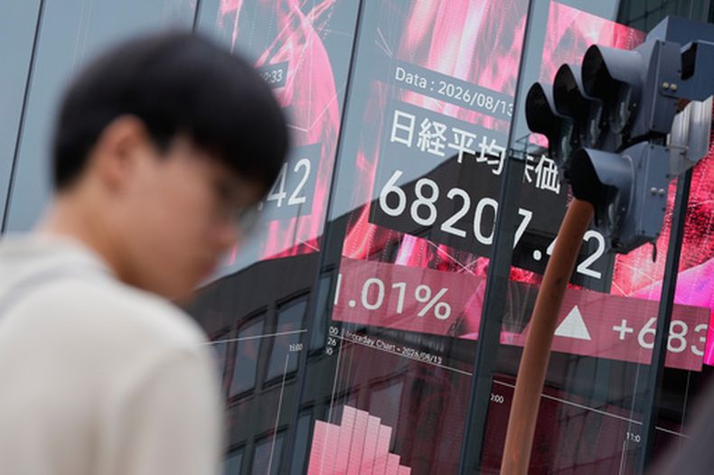 Una persona se encuentra frente a un tablero electrónico que muestra el índice Nikkei de Japón en una correduría de valores el jueves 13 de agosto de 2026, en Tokio. (AP Foto/Eugene Hoshiko)