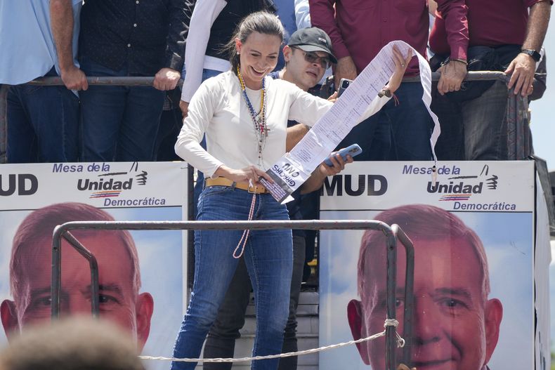La líder opositora María Corina Machado sostiene actas de recuento de votos durante una manifestación para protestar por los resultados oficiales que declararon al presidente Nicolás Maduro como ganador de las elecciones presidenciales de julio, en Caracas, Venezuela, el sábado 17 de agosto de 2024. (Foto AP/Ariana Cubillos)