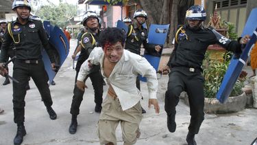americateve | Un trabajador camboyano herido huye de la polic&iacute;a antimotines en el complejo de una pagoda budista en Phnom Penh, Camboya, el 12 de noviembre de 2013. (Foto AP