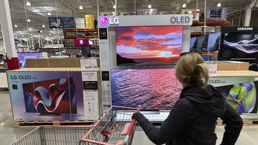 ARCHIVO - Una consumidora pasa frente a varios televisores en una bodega de Costco el 29 de abril de 2024, en Lone Tree, Colorado. (AP Foto/David Zalubowski, Archivo)
