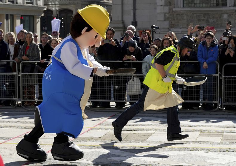 Corredores disfrazados compiten en una carrera tradicional de panqueques entre gremios en el Guildhall, Londres, el martes 4 de marzo de 2025. (AP Foto/Frank Augstein)