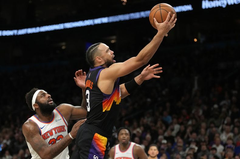 El alero Dillon Brooks (3), de los Suns de Phoenix, se enfila a la canasta superando al pívot Mitchell Robinson, izquierda, de los Knicks de Nueva York, para anotar en la segunda mitad del juego de baloncesto de la NBA, el viernes 9 de enero de 2026, en Phoenix. (AP Foto/Ross D. Franklin)