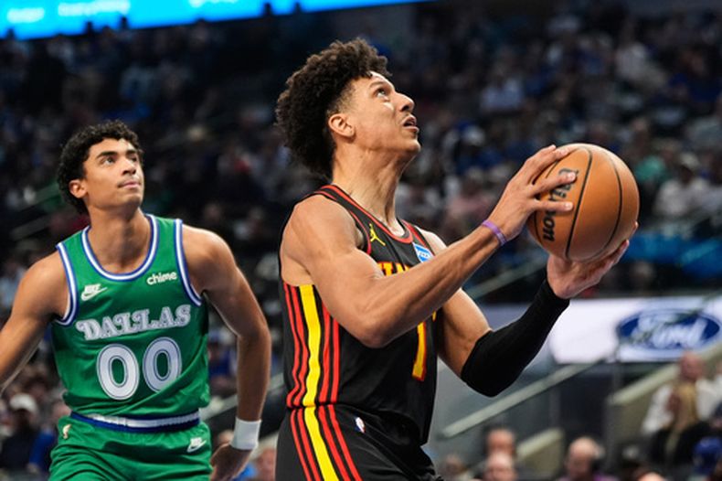 Jalen Johnson (1), de los Hawks de Atlanta, se enfila a encestar superando a Max Christie (00), de los Mavericks de Dallas, en la primera mitad del juego de baloncesto de la NBA, el miércoles 18 de marzo de 2026, en Dallas. (AP Foto/Tony Gutierrez)