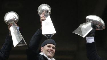 ARCHIVO - El entonces quarterback de los Patriots de Nueva Inglaterra, Tom Brady, sostiene el trofeo Vince Lombardi, entre otros que el equipo había ganado antes, durante un desfile en Boston para celebrar el triunfo de los Patriots en el Super Bowl del 7 de febrero de 2017 sobre los Falcons de Atlanta. (AP Foto/Elise Amendola, archivo)