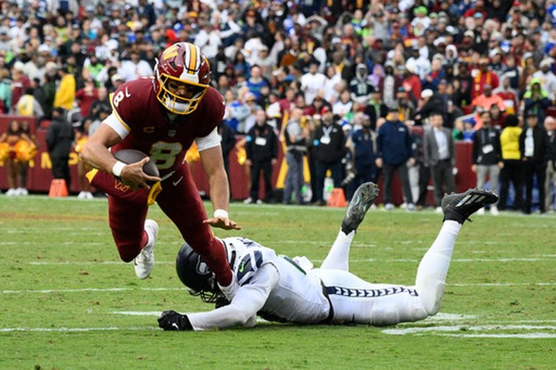 Marcus Mariota (8), quarterback de los Commanders de Washington es derribado por Ernest Jones IV (13), de los Seahawks de Seattle, durante la segunda mitad del partido de la NFL del domingo 27 de septiembre de 2026, en Landover, Maryland. (AP Foto/Nick Wass)