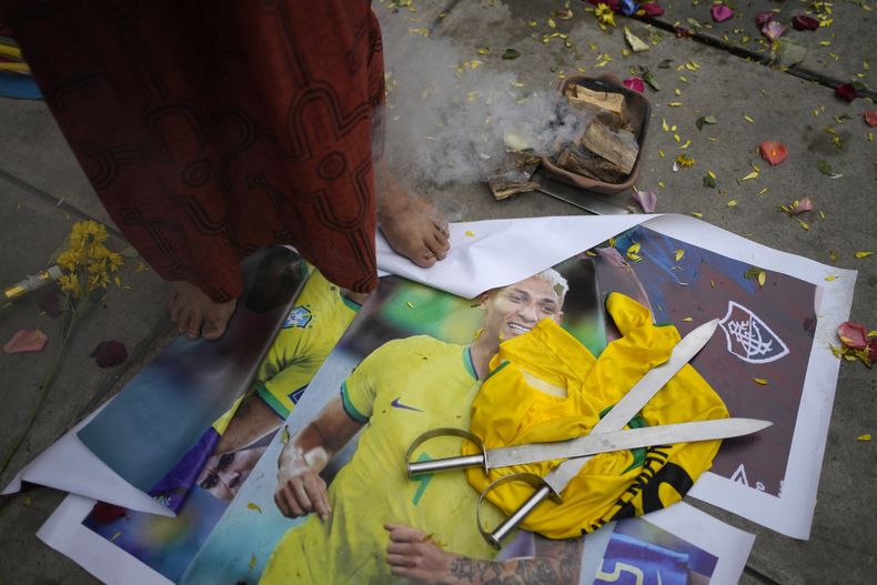Un chamán peruano de pie sobre una foto del delantero brasileño Richarlison al realizar un ritual de buena suerte para la selección de Perú afuera del estadio Nacional de Lima, el lunes 11 de septiembre de 2023. (AP Foto/Martin Mejía)