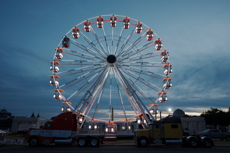La noria del National Mall se ve iluminada mientras continúa la preparación para una gran feria en el lugar, el domingo 21 de junio de 2026 en Washington. (AP Foto/Jon Elswick)