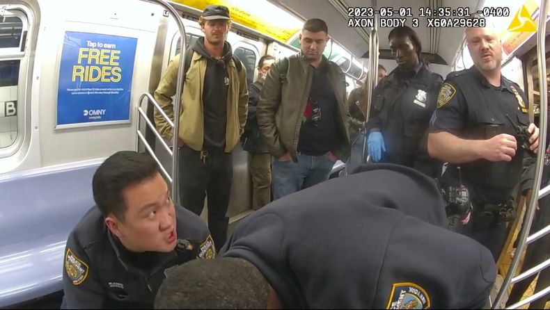 Foto tomada de video de una cámara corporal policial, entregada por el Departamento de Policía de Nueva York, que muestra Daniel Penny, de pie a la izquierda, en un vagón del tren subterráneo mientras agentes tratan de reanimar a Jordan Neely el 5 de mayo del 2023. (Departamento de Policía de Nueva York via AP)