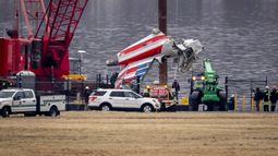 Una grúa descarga una pieza de los restos de un buque de salvamento en un camión de plataforma, cerca del lugar de los restos en el río Potomac de una colisión en pleno vuelo entre un avión de American Airlines y un helicóptero Black Hawk, en el Aeropuerto Nacional Ronald Reagan de Washington, el miércoles 5 de febrero de 2025, en Arlington, Virginia. (AP foto/Ben Curtis)