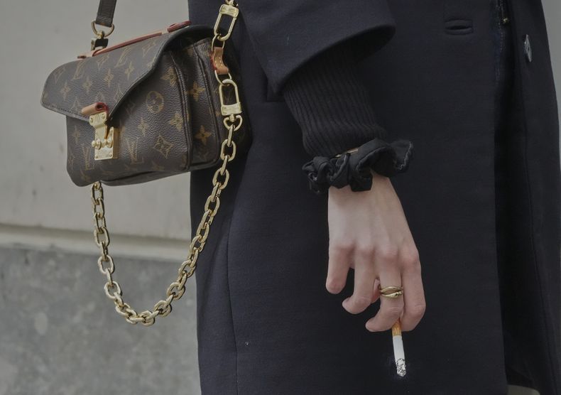 Una mujer sostiene un cigarrillo en la mano en una calle de París, el 28 de mayo de 2025. (AP Foto/Michel Euler)