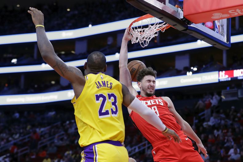 Alperen Sengun, derecha, de los Rockets de Houston, clava el balón frente a LeBron James (23), de los Lakers de Los Ángeles, durante la segunda mitad del juego de baloncesto de la NBA, el lunes 29 de enero de 2024, en Houston. (AP Foto/Michael Wyke)