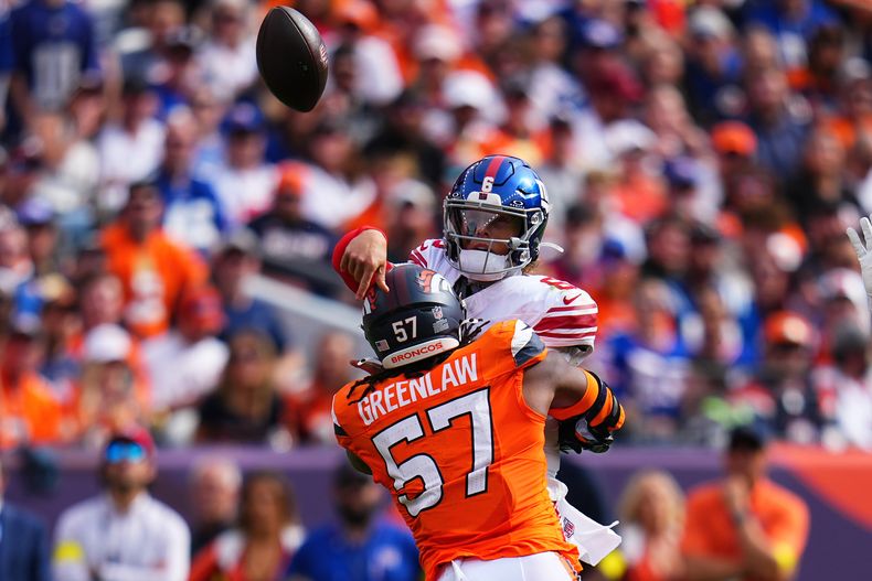 El linebacker Dre Greenlaw (57) de los Broncos de Denver golpea al quarterback Jaxson Dart de los Giants de Nueva York durante la primera mitad de un partido de fútbol americano de la NFL en Denver, el domingo 19 de octubre de 2025. (AP Photo/Jack Dempsey)