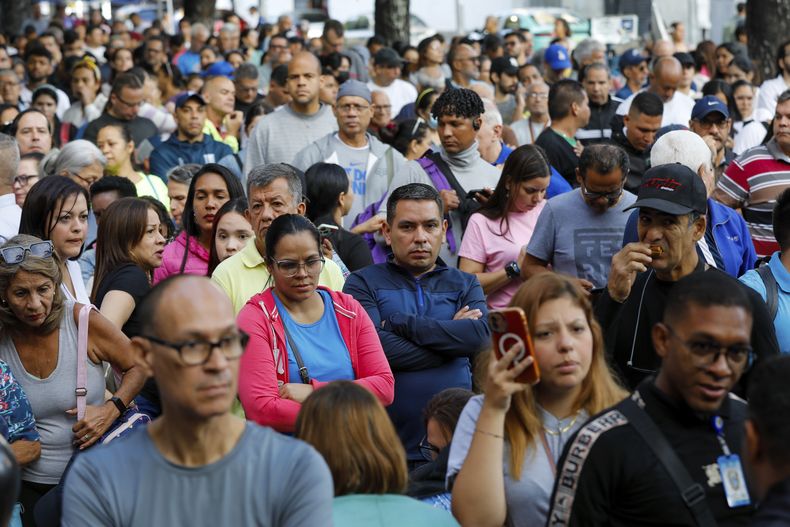 Venezolanos esperan afuera del centro de votación en la escuela Andrés Bello durante la elección presidencial en Caracas, Venezuela, el domingo 28 de julio de 2024. (AP Foto/Cristian Hernández)
