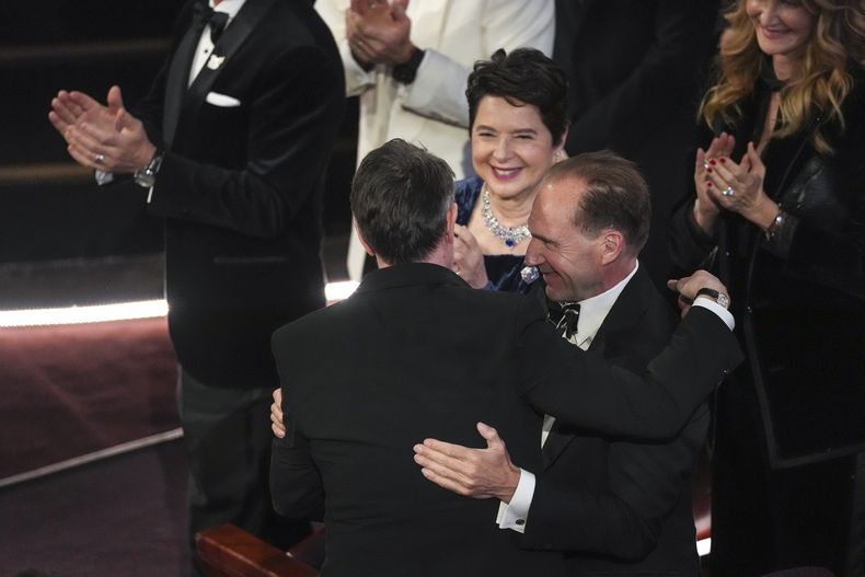 Isabella Rossellini, centro, y Ralph Fiennes, derecha, felicitan a Peter Straughan, izquierda, por ganar el premio al mejor guion adaptado por Conclave durante los Oscar el domingo 2 de marzo de 2025 en el Dolby Theatre de Los Ángeles. (Foto AP/Chris Pizzello)