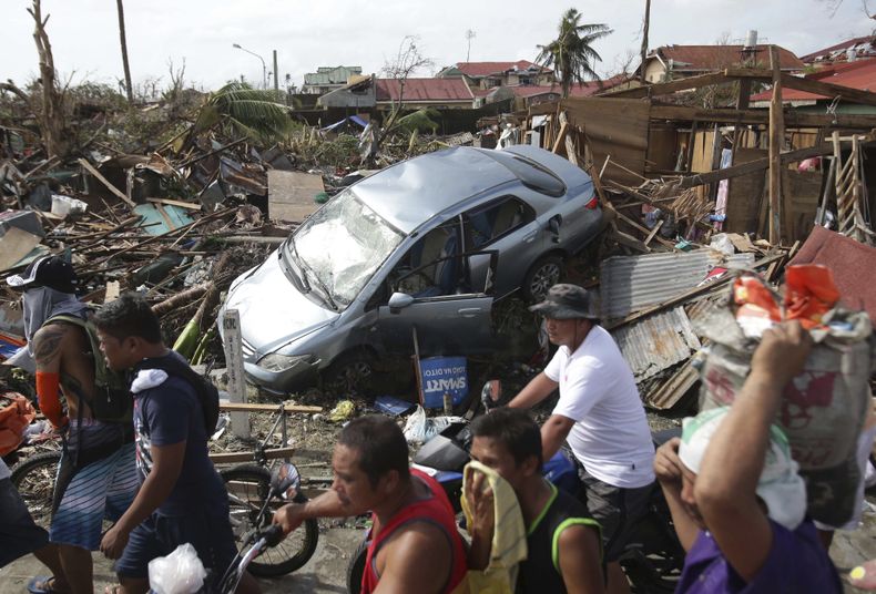 Sobrevivientes caminan frente a los da&ntilde;os causados por el tif&oacute;n Haiyan en la ciudad de Tacloban, centro de Filipinas, el lunes 11 de noviembre de 2013. La tormenta que devast&oacute; Filipinas dej&oacute; ocho muertos en el sur de China. (Fo